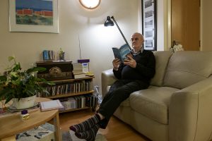 Older man in his well lit and warm living room. Looks very comfortable.